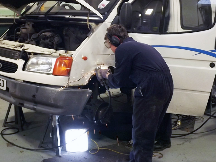 Student cutting out part of a wheel arch which he will replace with a new repair panel