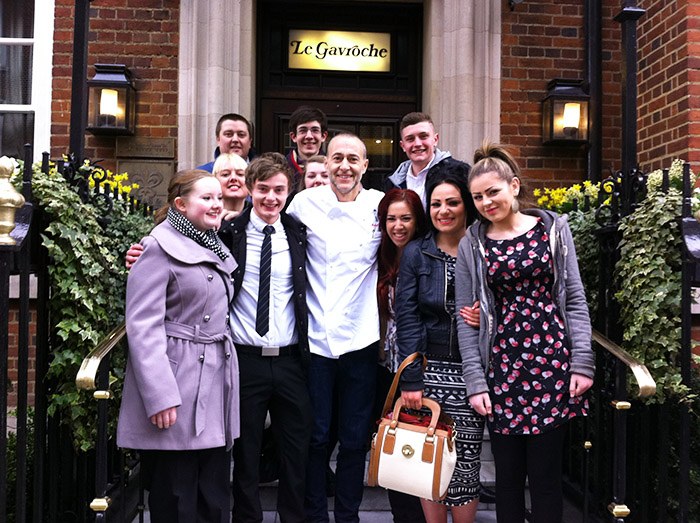 Students posing for a photo with chef de cuisine Michel Roux Jr outside the Le Gavroche Restaurant.
