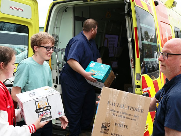 Students helping to load the ambulance with John